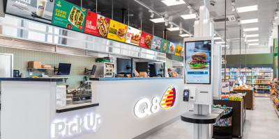 Borne en libre-service et comptoir à emporter dans une station-service Q8, avec sandwiches, burgers et snacks.